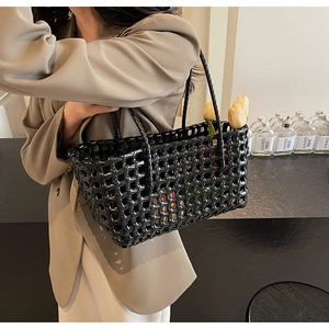 Close-up of black woven hollow tote bag with thin straps and decorative yellow tulips