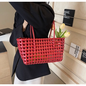 Detailed view of red woven leather tote bag with openwork mesh and elegant slim handles