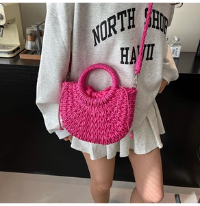 Detail of rose red woven straw handbag with drawstring closure and braided shoulder strap