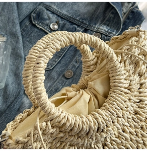 Close-up of straw woven handbag featuring circular handles and drawstring inner lining
