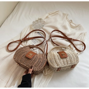 Detail showing two handwoven straw half-moon bags with leather handles and straps
