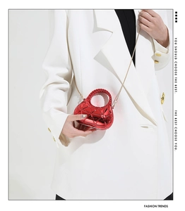 Detailed view of red metallic mini box bag with geometric texture and gold chain strap