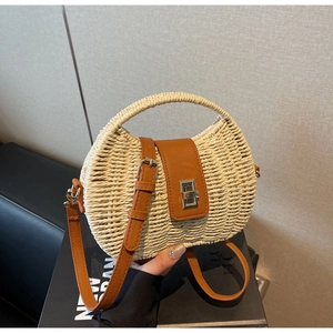 Close-up of woven straw handbag with brown leather flap and silver metal twist lock
