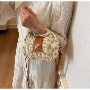 Detail of a beige straw handbag with brown leather flap and silver twist-lock closure