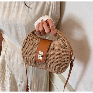 Close-up of straw beach bag with brown leather flap and metal twist-lock detail