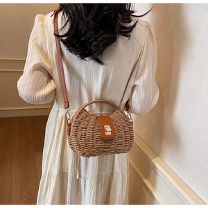 Detailed back view of a woven straw bag with brown leather strap in a warm home setting