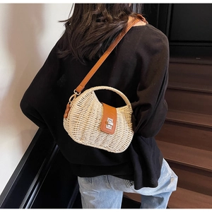 Close-up of straw beach bag with brown leather strap and silver twist-lock closure