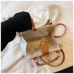 Detailed view of straw bag interior showing large storage space and bamboo handle