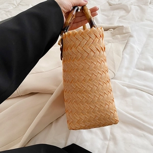 Handmade woven bucket bag with vintage bamboo handles and natural straw texture