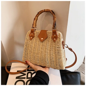 Detail of hand-woven straw handbag with natural bamboo handle and brown leather clasp