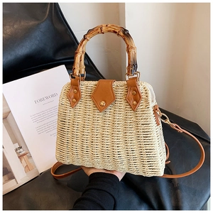 Close-up of retro straw handbag featuring a bamboo handle and brown leather corner details