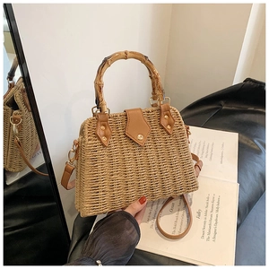 Detail of hand-woven straw bag featuring a bamboo handle and brown leather flap