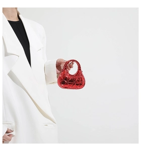 Macro view of bright red acrylic mini box bag with metallic geometric texture held by a hand