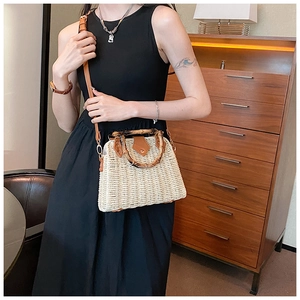 Detail of hand-woven straw bag with bamboo handle and brown leather flap for summer style