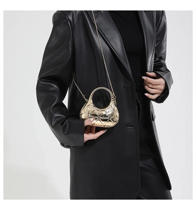 Mini golden crescent acrylic evening bag with quilted pattern shown on a leather coat