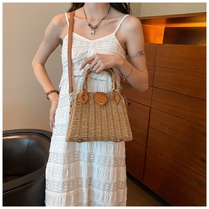 Close-up of retro straw handbag featuring a bamboo handle and brown leather shoulder strap