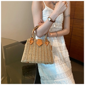 Close-up of woven straw handbag with bamboo handle and premium leather accents