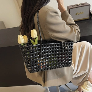 Fashionable black hollow woven tote bag with handle shown on a model for beach outings