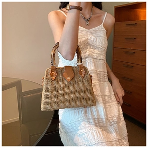 Detail of hand-woven straw bag with bamboo handle and brown leather connectors