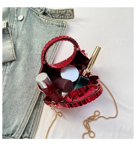 Red shell-shaped acrylic clutch bag showing interior space for lipstick and cosmetics