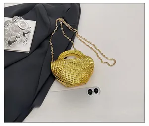 Dettaglio della borsa a tracolla intrecciata oro accanto a uno smartphone per le dimensioni