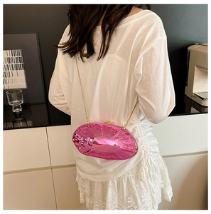 Pochette rosa metallizzata a conchiglia con catena dorata indossata in interno moderno