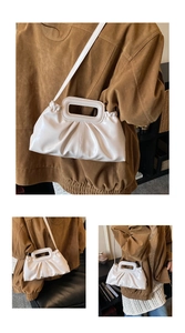 Detail of white pleated cloud bag with unique rectangular cutout handle and faux leather finish