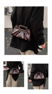 Detail of dark brown pleated handbag with rectangular handle and street style backdrop