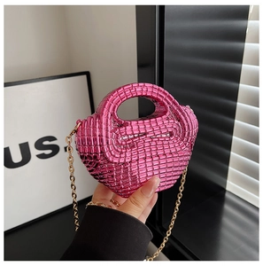 Detail of rose red woven mini bag with gold chain strap held against minimalist decor