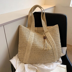 Large capacity straw bucket bag with tassel detail on modern chair for summer vacation