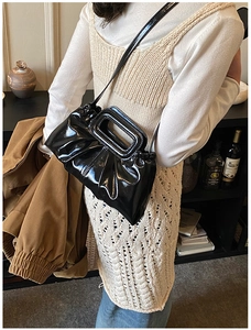 Detail of glossy pleated black leather shoulder bag with vintage rectangular handle