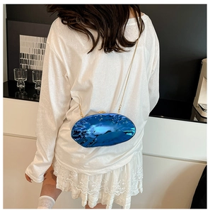 Dettaglio borsa a tracolla blu metallizzato con texture ondulata e catena dorata su modella