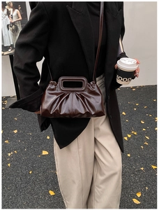 Detail of dark brown glossy pleated shoulder bag with rectangular cutout handle