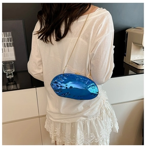 Dettaglio borsa a tracolla ondulata blu elettrico con finitura metallica e catena oro