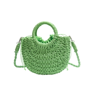 Handmade green woven half-moon straw bag with top handles and a crossbody strap
