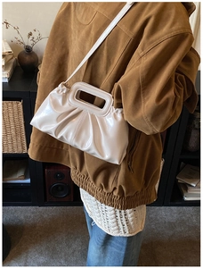 Detail of off-white pleated tote bag with vintage cutout handle and glossy synthetic leather