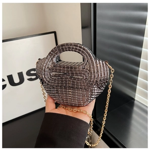 Detail of gunmetal mini hardshell bag with woven texture and gold chain strap