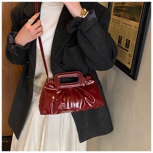 Detail view of burgundy pleated glossy handbag with unique rectangular frame handle