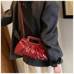 Detail of dark red patent leather crossbody bag with pleated texture and rectangular handle