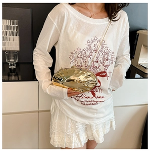 Clutch dorata a forma di fagiolo con texture martellata e tracolla a catena indossata