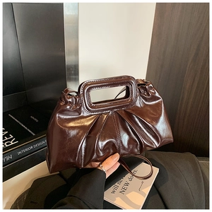 Close-up of a glossy dark brown cloud bag with a unique rectangular hollow handle