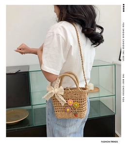 Dettaglio di borsa in paglia intrecciata con fiocchi in pizzo e decorazioni floreali 3D