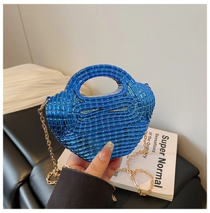Detail of electric blue woven mini bag with gold chain strap held against dark background