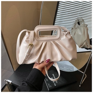 Close-up of beige ruched cloud bag featuring square cut-out handles and gold metal details