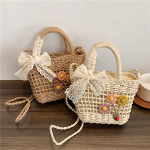 Dettaglio borsa in paglia intrecciata con fiori all'uncinetto e fiocco in pizzo decorativo