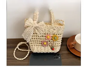 Dettaglio della borsa in paglia intrecciata con fiocco di pizzo e fiori in feltro