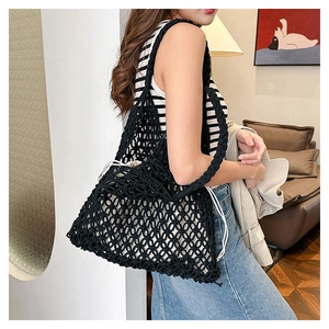 Detail of black hand-woven mesh shoulder bag with white drawstring inner pouch