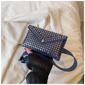 Detail view of navy envelope waist bag with silver stud accents on white suit background