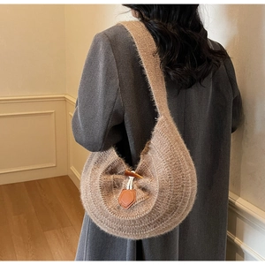 Détail d'un sac à bandoulière en maille peluche marron avec fermoir à bascule sur manteau