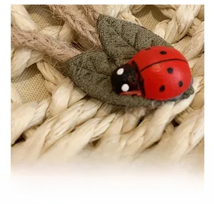 Vista macro di ciondolo coccinella su foglie verdi e trama di paglia intrecciata